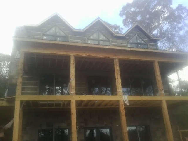 Dormers and porch framing on a large log home under construction — Roof Coating work by our crew in Hancock