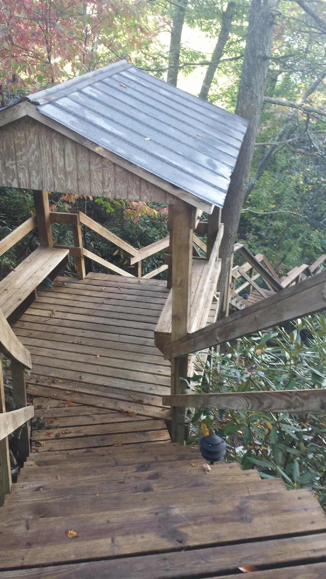 Metal roofed shelter over wooden steps on a wooded walkway — Skylight Repair & Installation work by our crew in Hancock